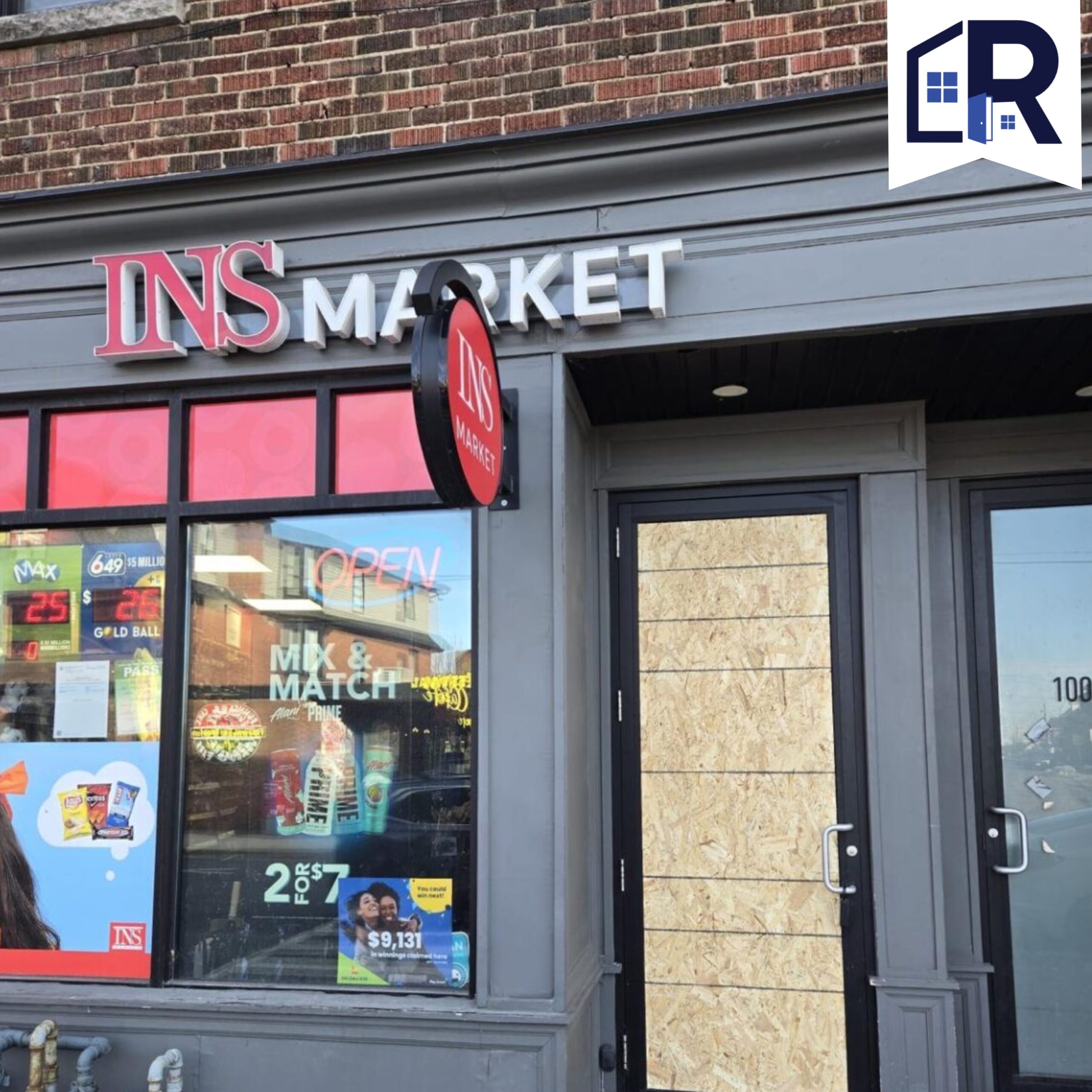 Commercial storefront with boarded door after glass damage repair.